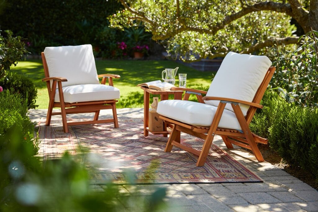un coin détente dans un jardin avec des fauteuils confortables et un tapis d'extérieur